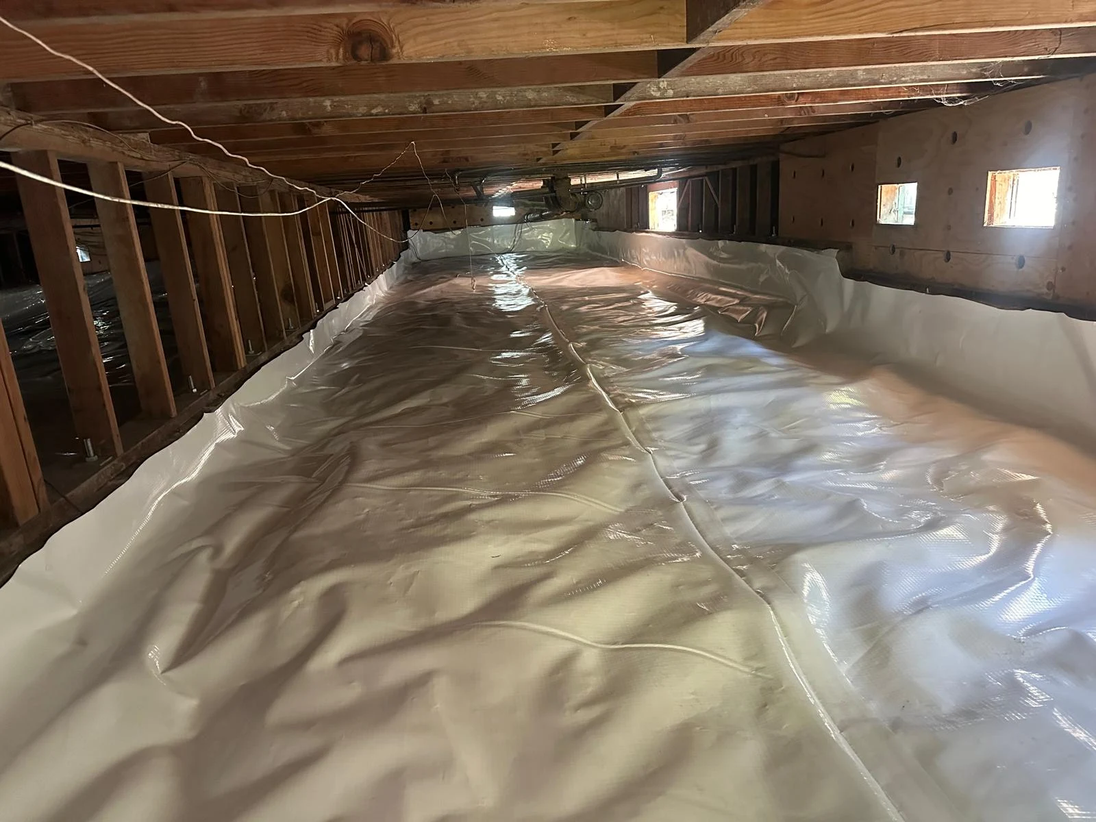 Crawlspace encapsulation with a white vapor barrier covering the ground