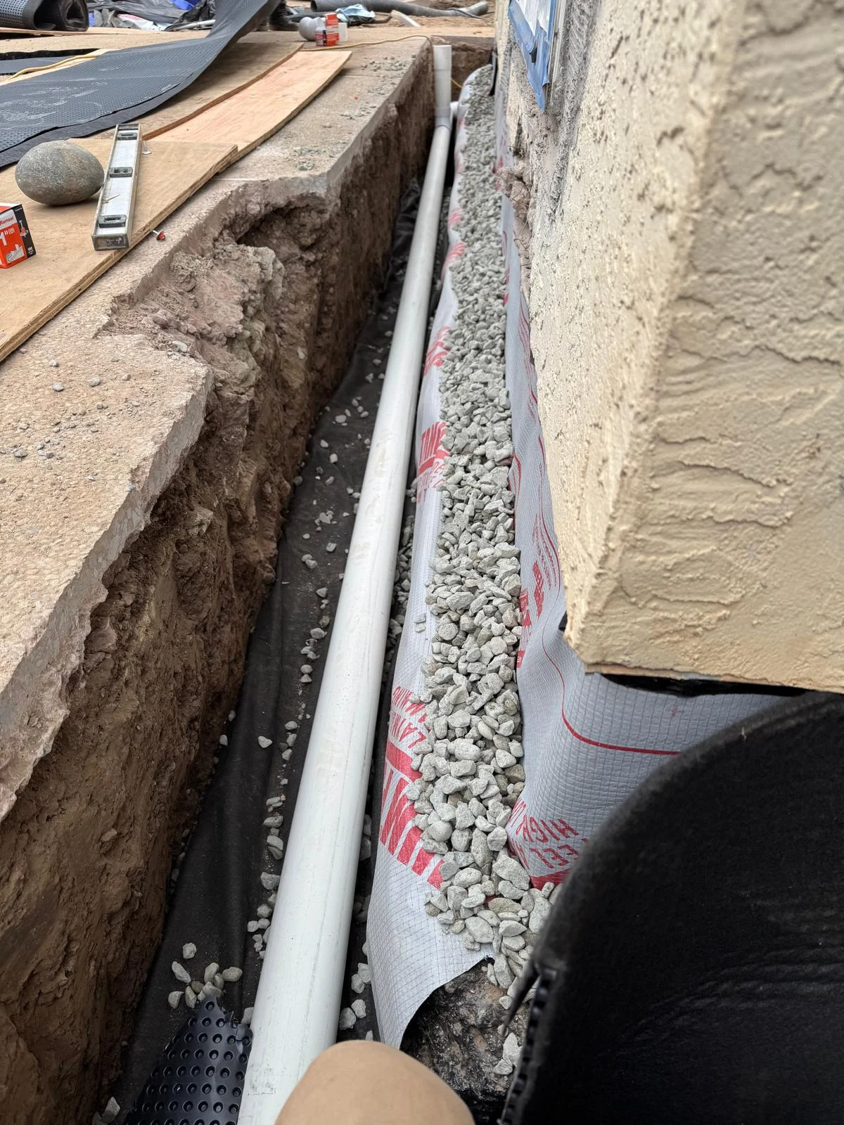 Lined trench for subsurface drainage beside a building
